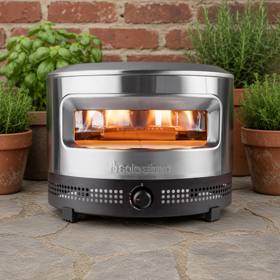 Solo Stove Pi Prime in stainless steel on a stone patio, flame lit inside