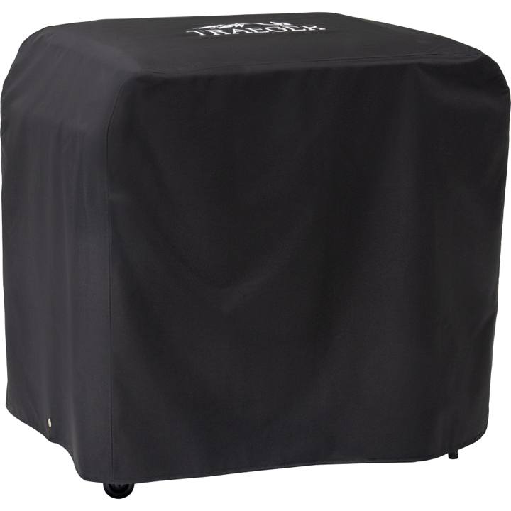 Black Traeger BAC889 cover drawn over a Flatrock 3 Zone griddle, white Traeger logo on the lid, casters showing below