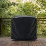 Traeger Flatrock cover fitted over the griddle on a wooden deck, with a metal railing and trees behind