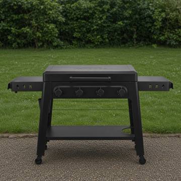 Black Traeger Irontop 4-burner griddle on wet gravel, lid closed, four control knobs and both side shelves out