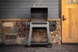 Traeger Westwood with the lid raised on a stone patio, both cooking racks empty and visible from the front