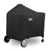 Black Weber cover over a Performer kettle and its full-width cart table, wheels and casters showing below the hem