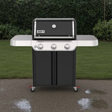 Weber Genesis E-315 front-on on wet gravel, lid closed, three knobs on a stainless panel, red caster locks visible