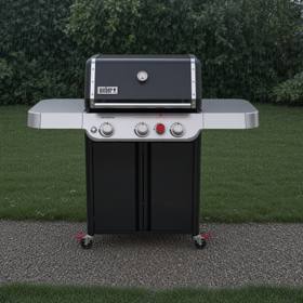 Black Weber Genesis E-325 gas grill on wet gravel beside a lawn, lid closed, hedge behind