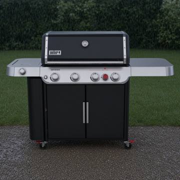 Black Weber Genesis E-435 gas grill on wet gravel, lid closed, red Sear Zone knob on the panel