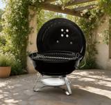 Weber Jumbo Joe 18 inch kettle on a stone terrace under a pergola, lid propped open on the grate