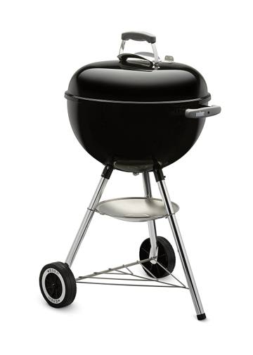 Black Weber 18 inch kettle with lid closed, three legs, two wheels and an ash pan, on a white background