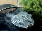 Close-up of the stamped aluminium lid damper on the Weber kettle, vents part open, smoke drifting across