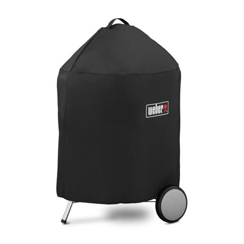 Black Weber Premium cover with a top loop handle over a 22 inch kettle, one wheel and leg below the hem