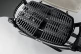 Overhead view of the Weber Q 1200 cast iron cooking grate with the cream lid open behind it