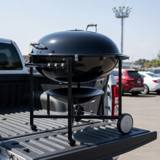 Weber Ranch Kettle 37 charcoal grill on its steel cart, loaded on a pickup tailgate in a car park
