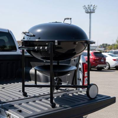 Weber Ranch Kettle 37 charcoal grill on its steel cart, loaded on a pickup tailgate in a car park