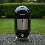 Weber Smokey Mountain Cooker Smoker 22 standing on gravel, black barrel, aluminum fuel door, lid thermometer