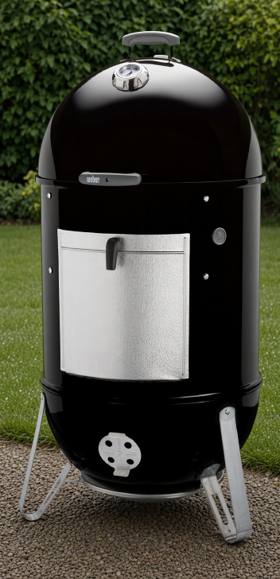 Weber Smokey Mountain Cooker Smoker 22 standing on gravel, black barrel, aluminum fuel door, lid thermometer