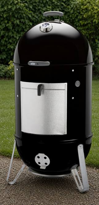 Weber Smokey Mountain Cooker Smoker 22 standing on gravel, black barrel, aluminum fuel door, lid thermometer