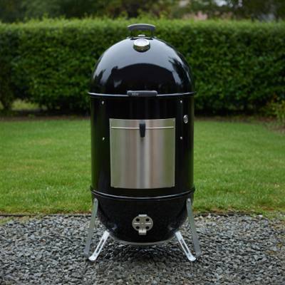 Weber Smokey Mountain Cooker Smoker 22 standing on gravel, black barrel, aluminum fuel door, lid thermometer