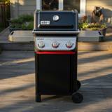 Weber Spirit E-325 front-on on a timber deck, lid closed, three control knobs and a red Sear Zone strip
