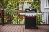Weber Spirit E-425 on a composite deck behind a black railing, lid closed, both side tables out