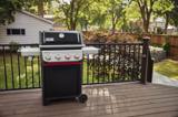 Weber Spirit E-435 on a composite deck behind a black metal railing, lid closed, both side tables extended