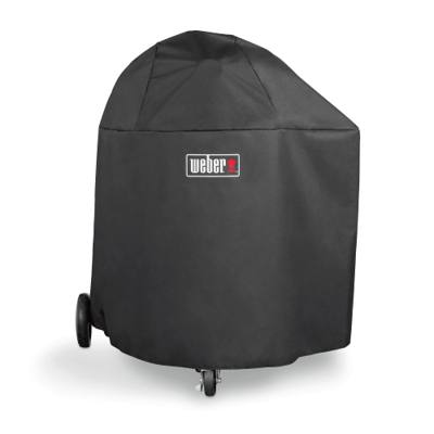 Black Weber cover with a logo patch pulled over a Summit kamado, two wheels and a front caster showing below the hem