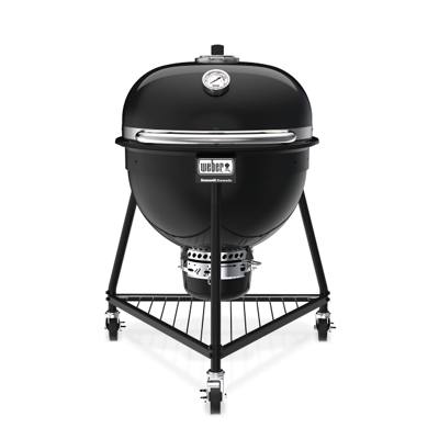 Weber Summit Kamado E6 in black, lid closed, on its three-caster tripod stand with a wire bottom rack